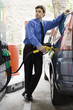 Well-dressed man refueling vehicle at gas station
