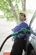 Well-dressed man refueling vehicle at gas station