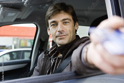 Photo: Mid-adult man in drive-thru handing credit card to check-out window clerk Mid-adult man in drive-thru handing credit card to check-out window clerk