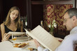 Mature couple looking at menus in restaurant