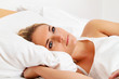 Frau liegt wach im Bett.