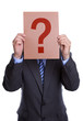 Photo: Man covering his face with a question mark sign Man covering his face with a question mark sign