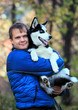 Photo: Portrait of young man holding his husky dog outdoors Portrait of young man holding his husky dog outdoors