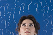 thinking business woman in front of question marks