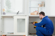 Foto: Good looking handyman fixing a door Good looking handyman fixing a door