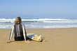 Surfer sitting with his surfboard at the beach