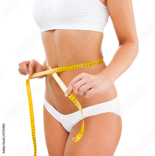 Photo: Woman measuring her slim body isolated on white Woman measuring her slim body isolated on white