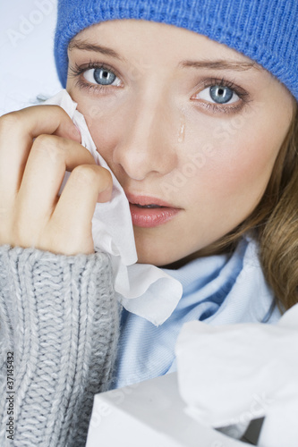 A woman crying, wiping her tears away with a tissue A woman crying, wiping her tears away with a tissue