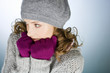 A young woman wearing hat and gloves, trying to keep warm