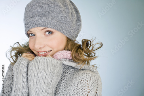 Photo: Portrait of a young woman wearing a grey woollen hat, smiling Portrait of a young woman wearing a grey woollen hat, smiling