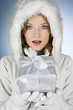 A young woman wearing a winter coat, holding a Christmas present