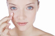 A young woman with blue eyes, finger touching her face