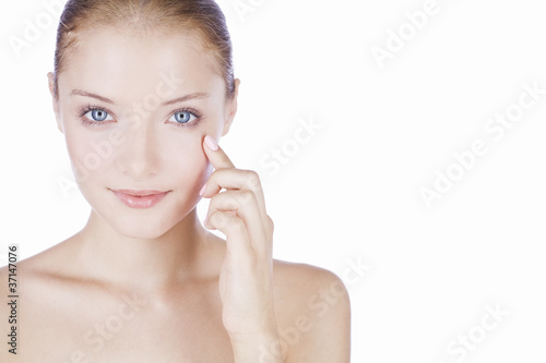 Foto: A young woman with blue eyes, finger touching her face A young woman with blue eyes, finger touching her face