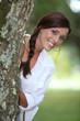 Smiling woman leaning out from behind a tree
