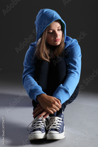 Photo: Blonde teenager girl alone and sad in blue hoodie Blonde teenager girl alone and sad in blue hoodie