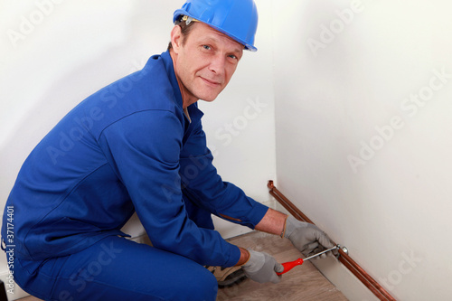 Photo: Plumber screwing copper water pipes in place Plumber screwing copper water pipes in place