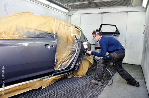 Photo: Worker painting a car. Worker painting a car.