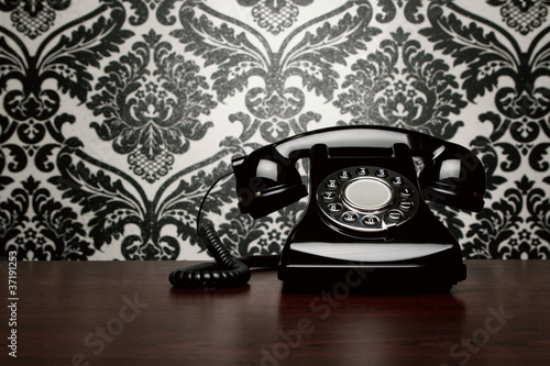 Photo: Vintage telephone over ornate wallpaper with copy space Vintage telephone over ornate wallpaper with copy space