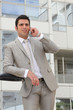 Businessman stood outside office with mobile telephone