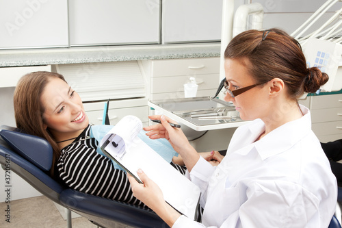 Photo: Dentist taking notes while young patient smiling Dentist taking notes while young patient smiling