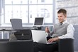 Smiling businessman working on laptop in office