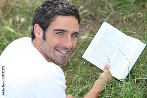 Photo: a man lying on grass is reading a book a man lying on grass is reading a book