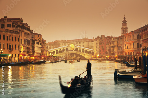 Rialto Bridge and gondolas at a foggy autumn evening in Venice.