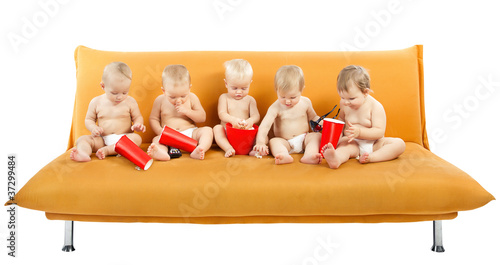 Photo: Group of children sitting on sofa and eating popcorn. Isolated w Group of children sitting on sofa and eating popcorn. Isolated w