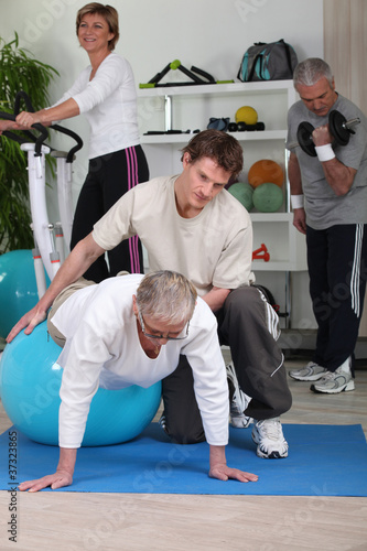 Photo: Older people working out with a personal trainer in a gym Older people working out with a personal trainer in a gym
