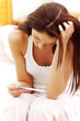 Photo: Worried woman looking at a pregnancy test in the bedroom. Worried woman looking at a pregnancy test in the bedroom.