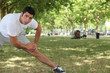 young man doing stretching exercises in park