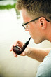 man smoking a pipe, river on background man smoking a pipe, river on background