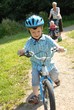 Foto: Child with bike and grandmother in background Child with bike and grandmother in background