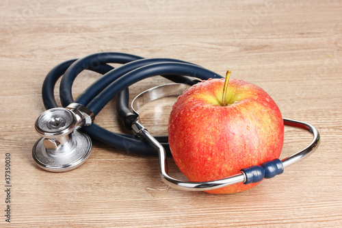 Photo: Medical stethoscope and red apple on wooden background Medical stethoscope and red apple on wooden background