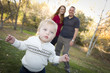 Cute Young Boy Walking as Parents Look On From Behind