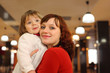 mother with little smiling daughter stand in empty cafe