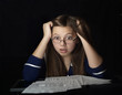 The amazed young woman wearing glasses, sitting at a table among