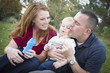 Young Parents Blowing Bubbles with their Child Boy in Park