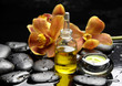 candle and orchid with bottle of essential oil on pebbles candle and orchid with bottle of essential oil on pebbles