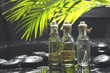 bottle of essential oil and green palm leaf with stones