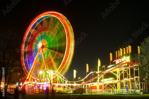 Foto: Amusement park at night - ferris wheel and rollercoaster Amusement park at night - ferris wheel and rollercoaster