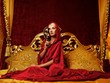 Beautiful woman with a carnival mask sitting in bed