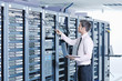 Foto: businessman with laptop in network server room businessman with laptop in network server room