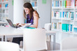 pretty female college student studying in the university library