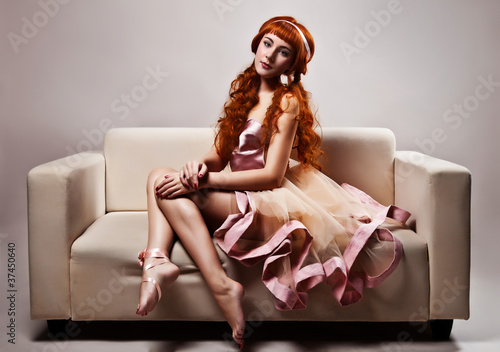Photo: The image of a beautiful woman in luxurious dress sitting on sof The image of a beautiful woman in luxurious dress sitting on sof