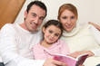 Parents reading a bedtime story to their daughter