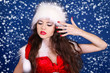 Girl in Santa Claus red dress posing on snow background