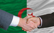 businessmen handshake after good deal in front of algeria flag businessmen handshake after good deal in front of algeria flag