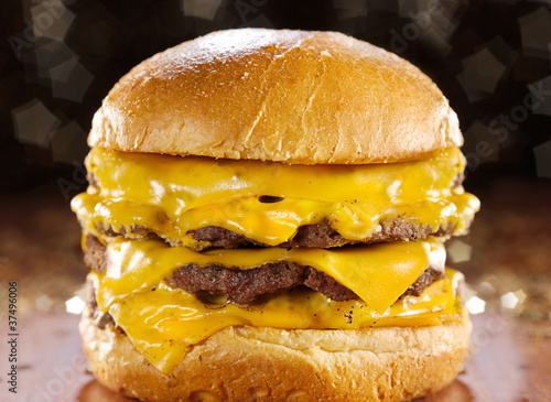 Photo: big cheeseburger with melted cheese and glittery background. big cheeseburger with melted cheese and glittery background.