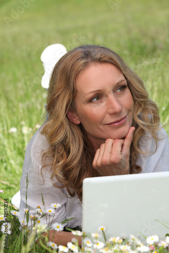 Photo: Woman on laptop in field Woman on laptop in field